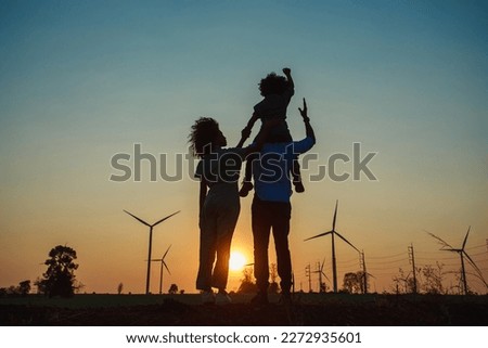 Silhouettes of Happy family father, mother and child daughter for hand and looking on windmill field at sunrise. windmills for electricity generation at sunrise by producing sustainable energy concept