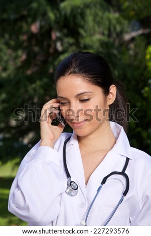 doctor young woman talking mobile over a green trees background 