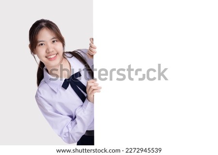 Happy pretty Asian student girl in school uniform holding white blank board beside with copy space.