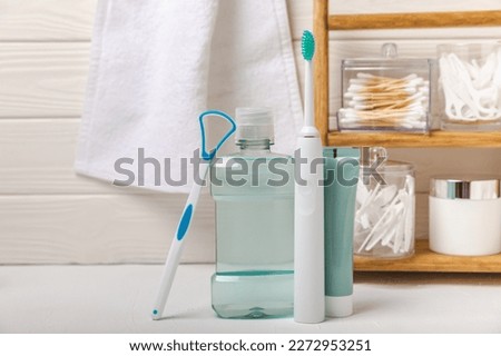 Electronic ultrasonic toothbrush, mouthwash, floss, tongue cleaner and toothpaste on white wooden background. Items for dental care and caries prevention in the bathroom. Dentistry concept. Copy space