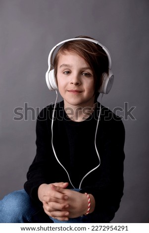 Sweet child, boy in black sweater, listening music, isolated background