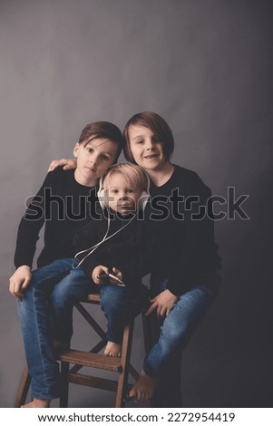 Sweet children, boy brothers in black sweaters, listening music, isolated background