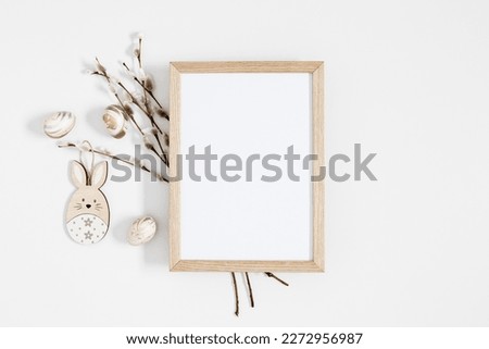 Easter trendy composition. Photo frame top view, willow plant branches, easter eggs and bunny on white background. Minimal concept Easter. Flat lay, top view, copy space