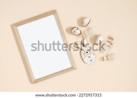 Easter trendy composition. Photo frame top view, feathers , easter eggs and bunny on beige background. Minimal concept Easter. Flat lay, top view, copy space