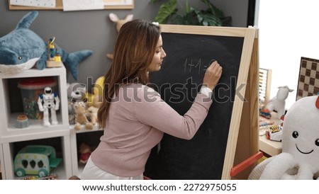 Young beautiful hispanic woman preschool teacher explaining maths exercise at kindergarten