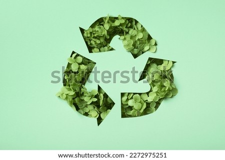 Green flowers under paper cut recycling symbol. Save planet recycling cloth concept.