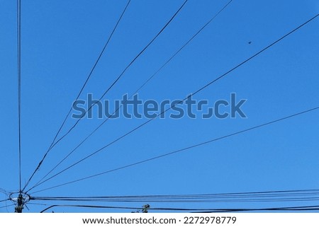 The silhouette view of cable lines with blue sky as background.