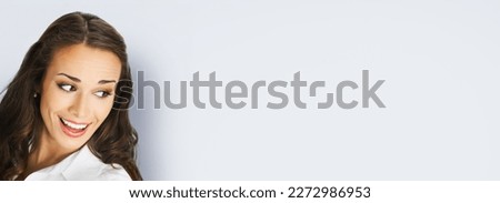 Happy excted smiling woman in white confident cloth looking aside. Business advertisement concept. Brunette businesswoman, isolated on grey gray background. Royalty-Free Stock Photo #2272986953