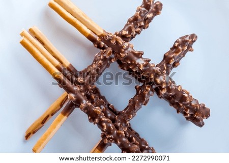 Chocolate covered pretzel sticks on a white plate.