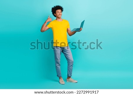 Full length photo of handsome guy hold netbook demonstrate thumb up isolated on teal color background