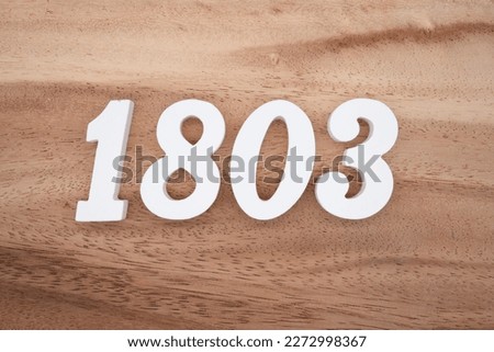White number 1803 on a brown and light brown wooden background.