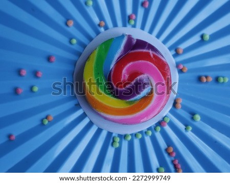 rainbow candy sprinkled with colored balls on a blue jar lid