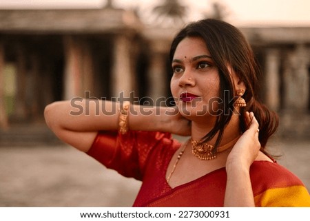 A selective focus of a young Indian woman in saree yellow and red coloured saree at Belur Chennakeshava Temple, Karnataka, India. Royalty-Free Stock Photo #2273000931