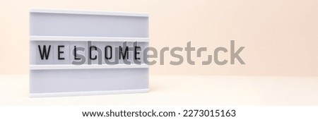 Banner with word Welcome. Lightbox with letters in front of beige background. Concept with place for text