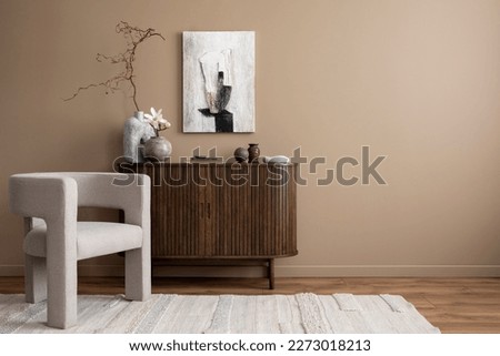 Creative composition of living room interior with mock up poster frame, copy space, wooden sideboard, vase with branch, gray armchair, beige rug and personal accessories. Home decor. Template.  Royalty-Free Stock Photo #2273018213
