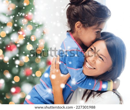 childhood, happiness, christmas, family and people concept - smiling little girl and mother hugging indoors over living room with tree