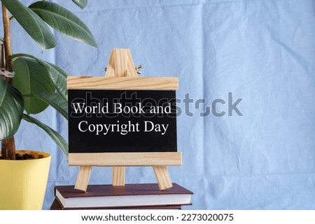 World Book and Copyright Day written on black board on stack of books on blue background with plants. book holiday, education concept 