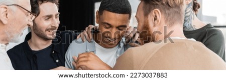 Cheerful group hugging african american man during anonymous alcoholics meeting in rehab center, banner Royalty-Free Stock Photo #2273037883