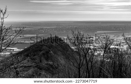 Cross on the mountain, in the background you can see the valley with the city and fields. Early spring, the trees are still without foliage. Ukraine.