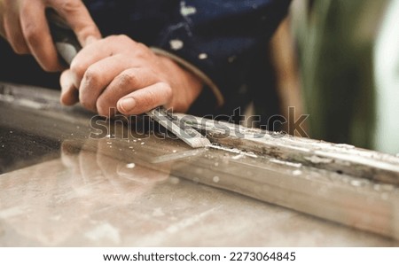 Carpenter renovating old wooden sash windows  -  removing old patty and scraping paint from the woodwork. Royalty-Free Stock Photo #2273064845