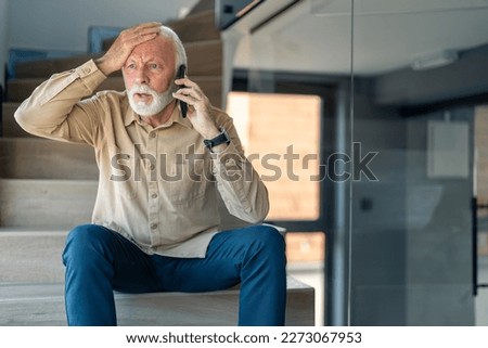 Worried senior man with hand on his head hearing bad news over cell phone, looking shocked and frustrated. Anxious senior man having dramatic unsatisfied conversation on mobile phone. Royalty-Free Stock Photo #2273067953