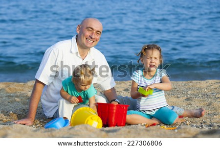Happy little girls with dad playing on  sea shore