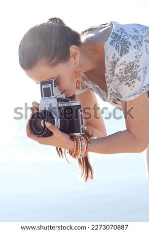 Young woman takes a photo with an old medium format film camera