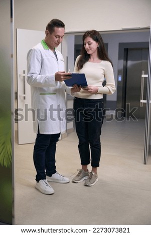 Male health worker communicates with a woman in hospital corridor