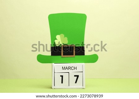 Happy St. Patrick's Day. Wooden calendar with March 17 date and leprechaun hat on green background