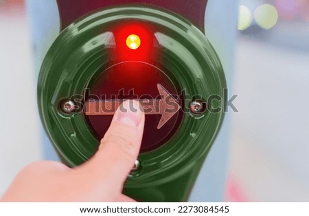 Close-up view of a thumb pressing a pedestrian crossing button, activating the signal to cross the road safely.