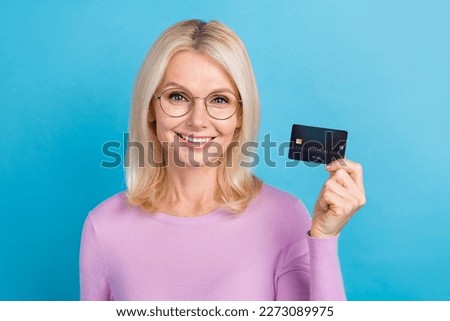 Photo of gorgeous glad successful lady wear stylish clothes arm hand hold card nfc payment shopping isolated on blue color background