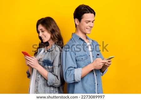 Photo of two cheerful satisfied people use telephone write typing blog post isolated on yellow color background