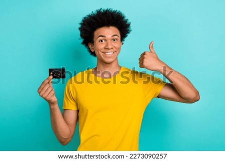 Photo of positive guy afro hairstyle dressed yellow t-shirt showing like approval hold card isolated on turquoise color background Royalty-Free Stock Photo #2273090257
