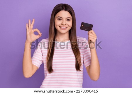 Photo of cute sweet girl dressed striped t-shirt showing okey sign rising credit card isolated purple color background