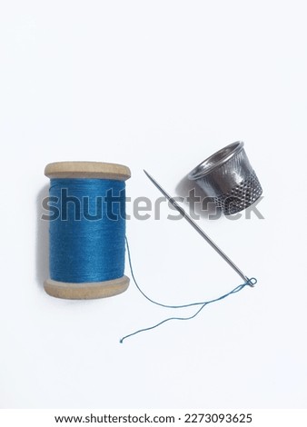 A spool of blue thread, thimble and needle Royalty-Free Stock Photo #2273093625
