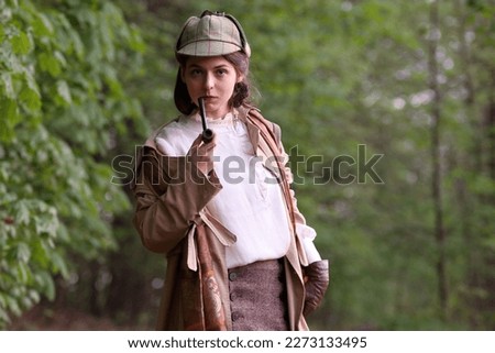 Young woman styled in sherlock holms hat with pipe in hand Royalty-Free Stock Photo #2273133495