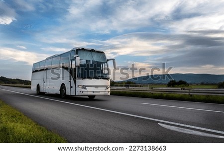 White Modern comfortable tourist bus driving through highway at bright sunny sunset. Travel and coach tourism concept. Trip and journey by vehicle Royalty-Free Stock Photo #2273138663