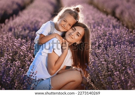 Happy family in purple lavender field. young beautiful mother and child Girl enjoy walking blooming meadow on summer day. Mom having fun with pretty daughter in nature on sunset. mothers day.