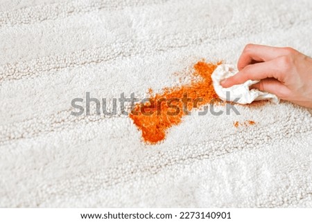Female's hand wiping a tomato stain on a white carpet indoors. Cleaning. closeup. daily life stain concept. High quality photo