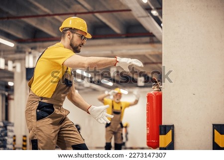 Young man using fire extinguisher in warehouse.Fire extinguishers. Royalty-Free Stock Photo #2273147307