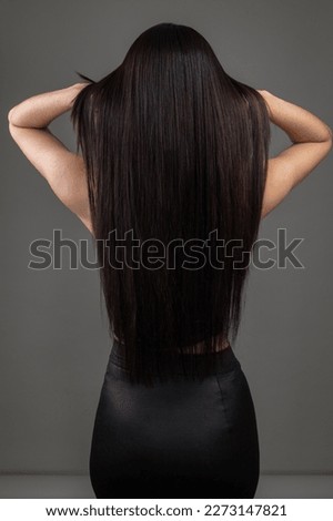 texture of long, black, straight silky hair of young woman on her back, silhouette of person in studio, salon hair care Royalty-Free Stock Photo #2273147821