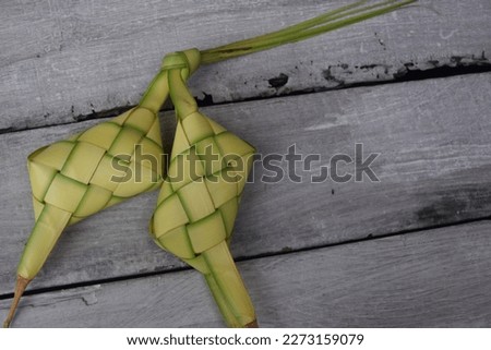 Ketupat or rice dumpling is a local delicacy during the festive season. Ketupat, a natural rice casing made from young coconut leaves for cooking rice on wooden background. Selective focus.