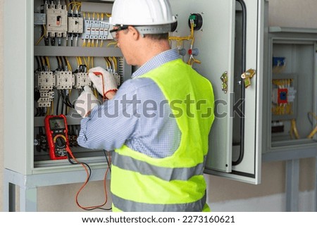 Electrician engineer work tester measuring voltage and current of power electric line in electical cabinet control.and wires on relay protection system. Bay control unit. Medium voltage switchgear. Royalty-Free Stock Photo #2273160621