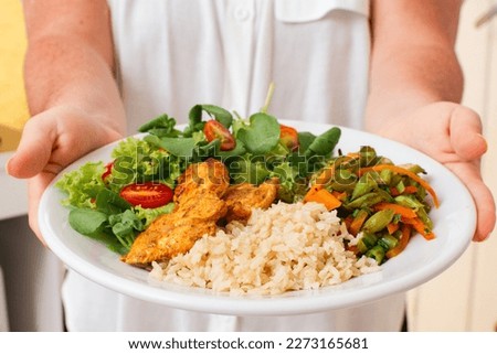 Healthy Meal with Grilled Chicken, Rice, Salad, and Vegetables Served by Woman