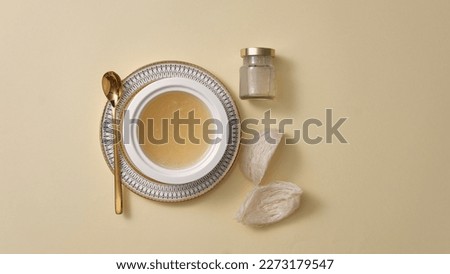 Top view of raw bird’s nest , bowl soup, and glass bottle without label on beige background. Mockup for products derived from natural bird's nest Royalty-Free Stock Photo #2273179547