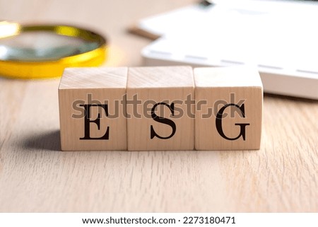 ESG on a wooden cubes with magnifier and calculator, financial concept background