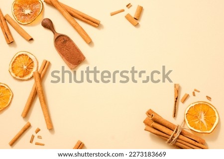 A lot of cinnamon (Cinnamomum) sticks scattered on a light background with cinnamon powder and some dried orange slices. Blank space to display product extracted from these herbals. Healthy concept Royalty-Free Stock Photo #2273183669