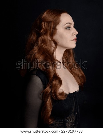  close up portrait of beautiful woman with long red hair wearing sheer corset top, variety of emotional expressions.  Isolated on dark studio background with. Moody silhouette lighting.