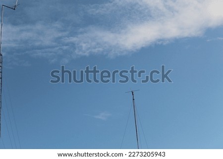 a clear blue sky and white clouds in the morning, seen from a distance of a radio transmitter antenna