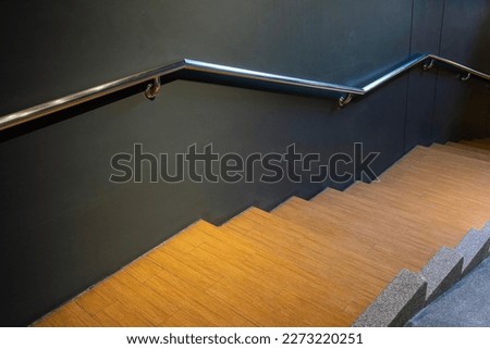 Modern wooden staircase with aluminium railing handle for safety.